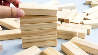 a hand stacking wooden blocks