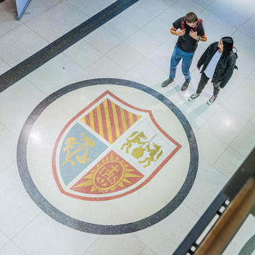two students in hallway with university seal on floor