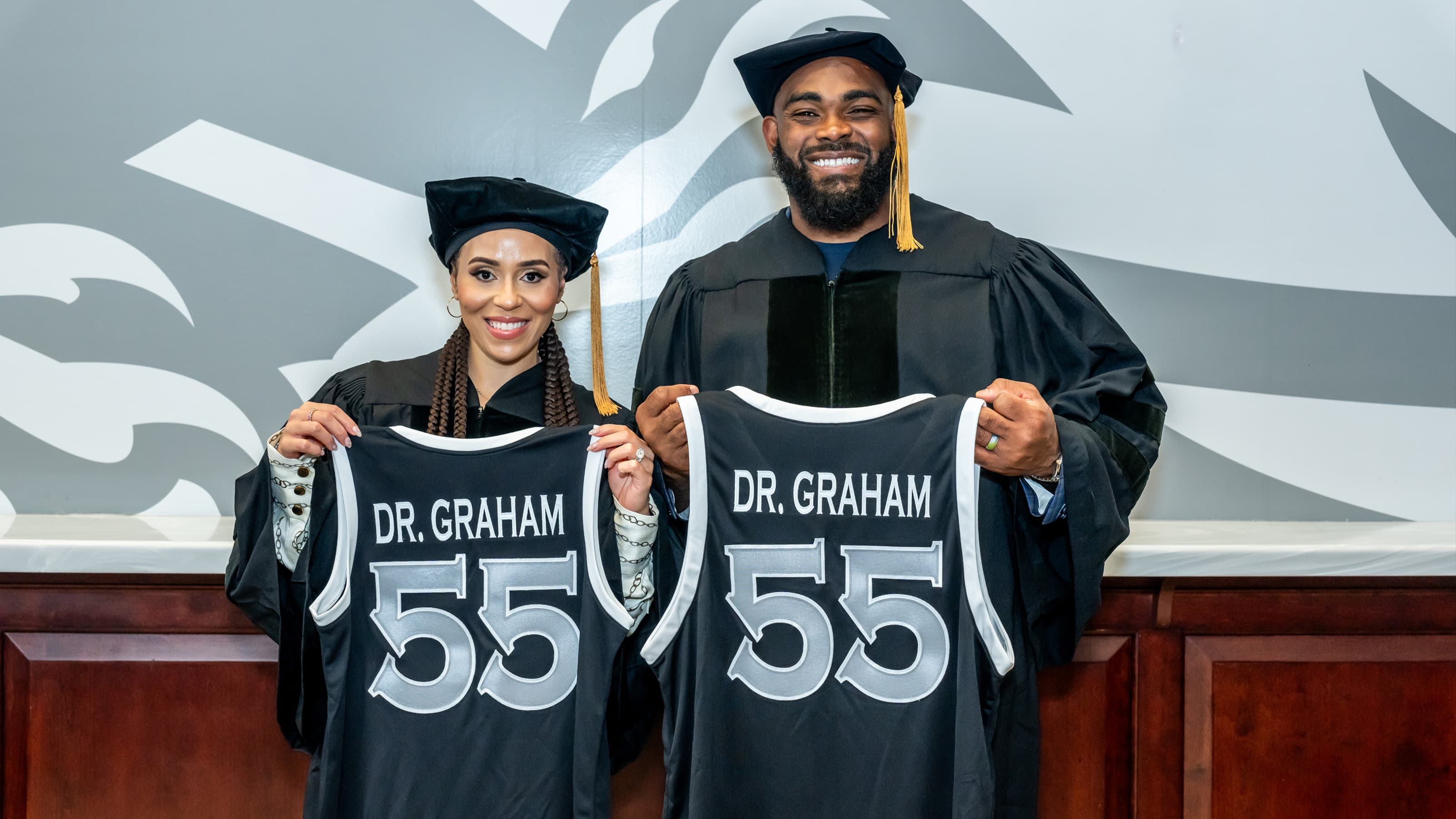 Carlyne and Brandon Graham in regalia holding "Dr. Graham" jerseys