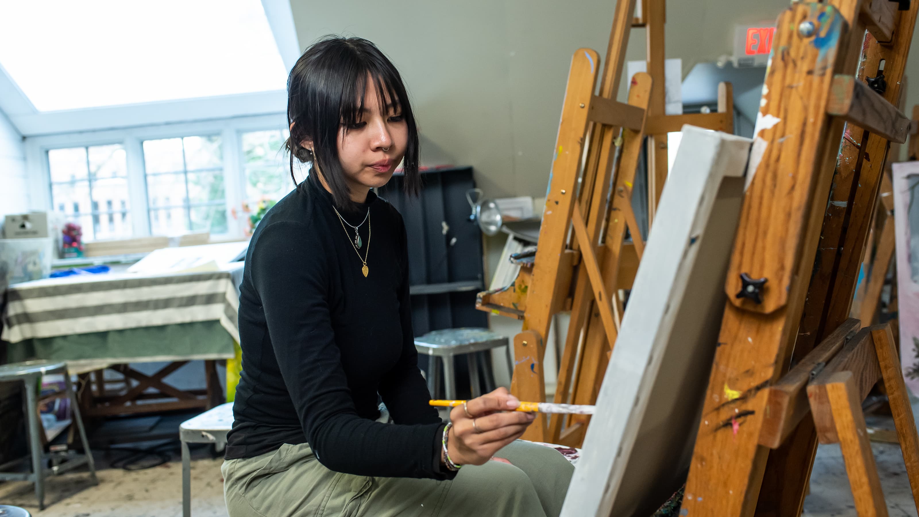 A student painting at an easel.