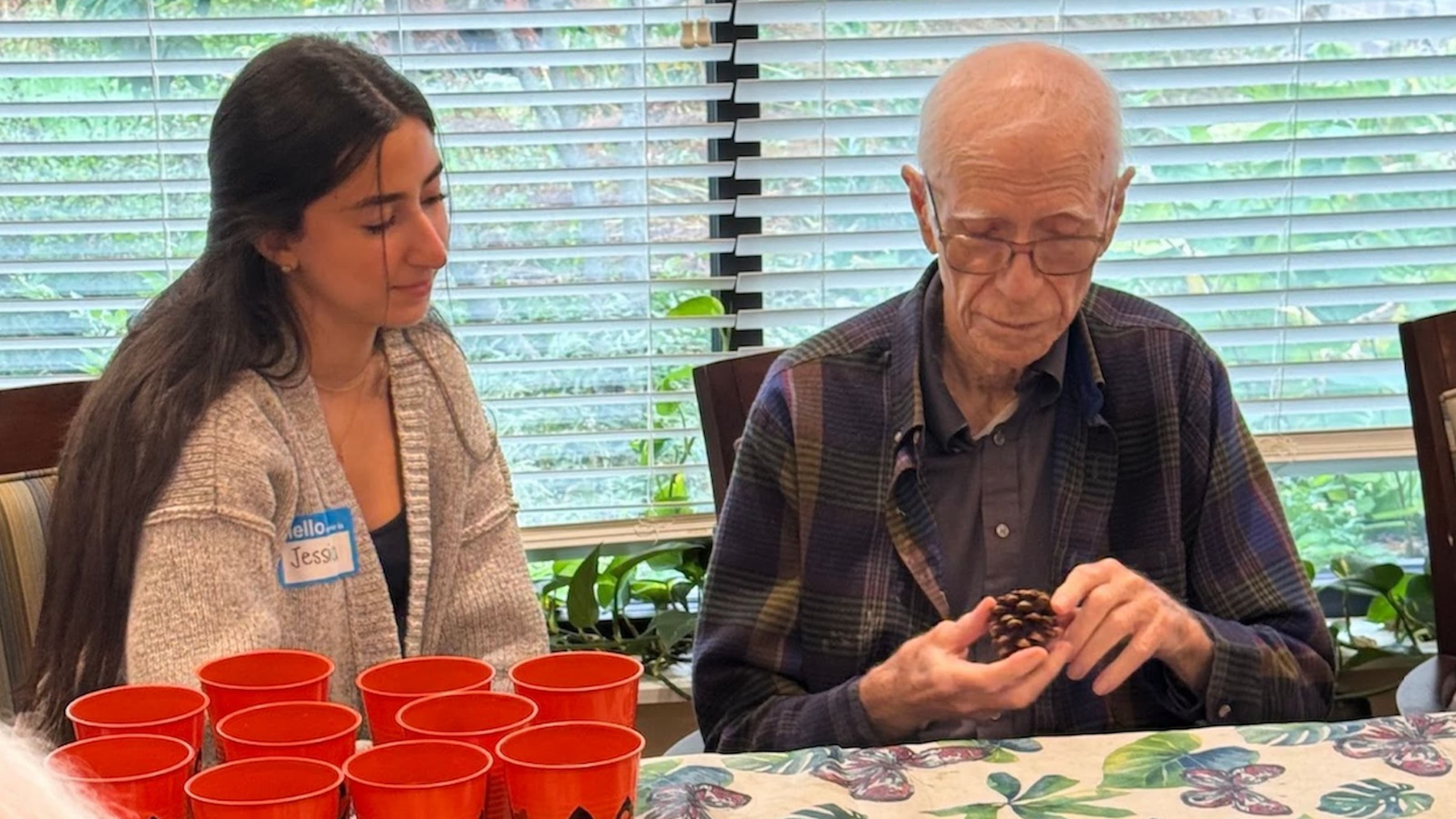 Jessica Haddad, BS ’26, sits with Anthony Berret, S.J., on a Halloween-themed plant project.