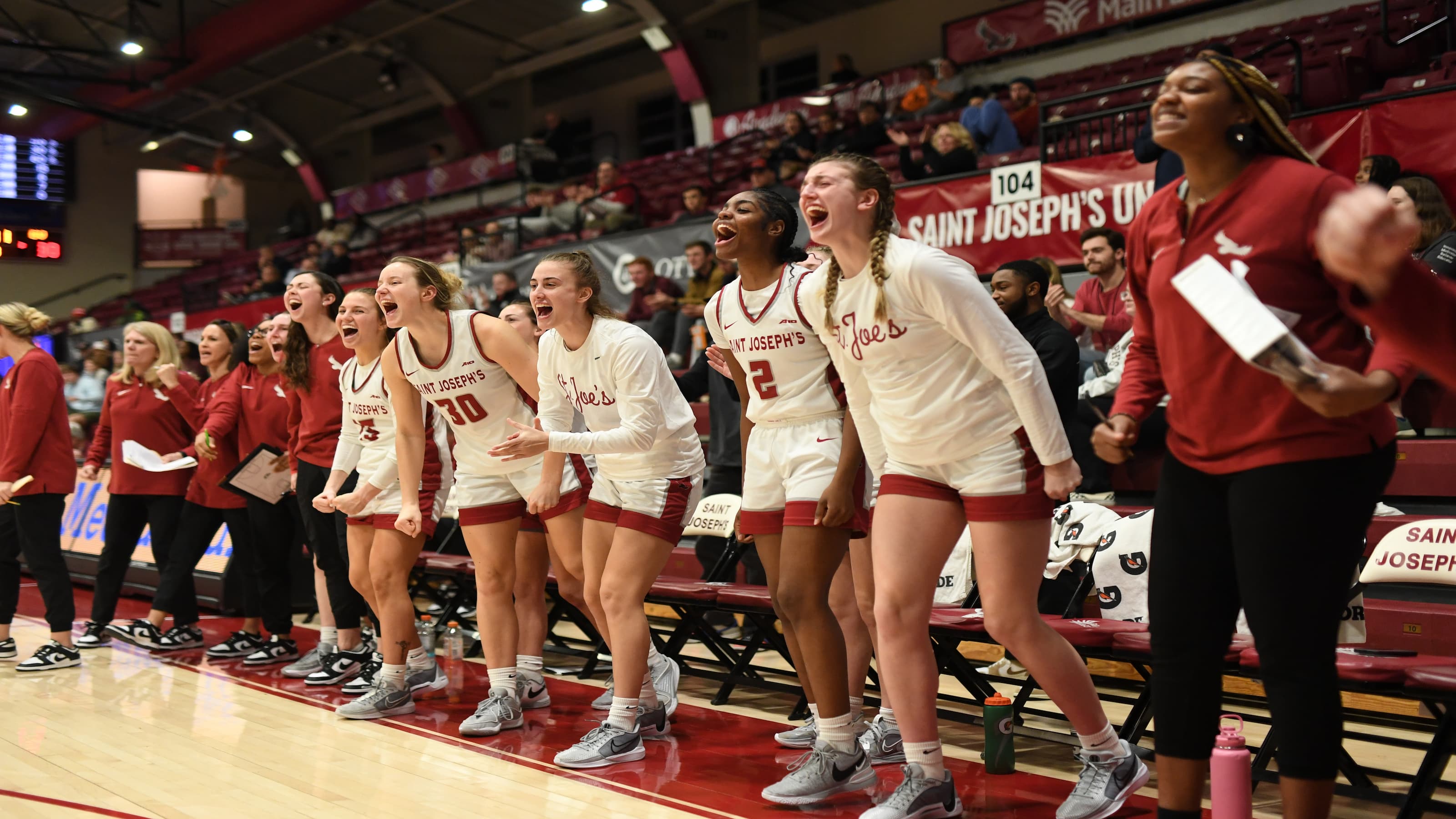 The SJU women's basketball team celebrates on the sidelines. 