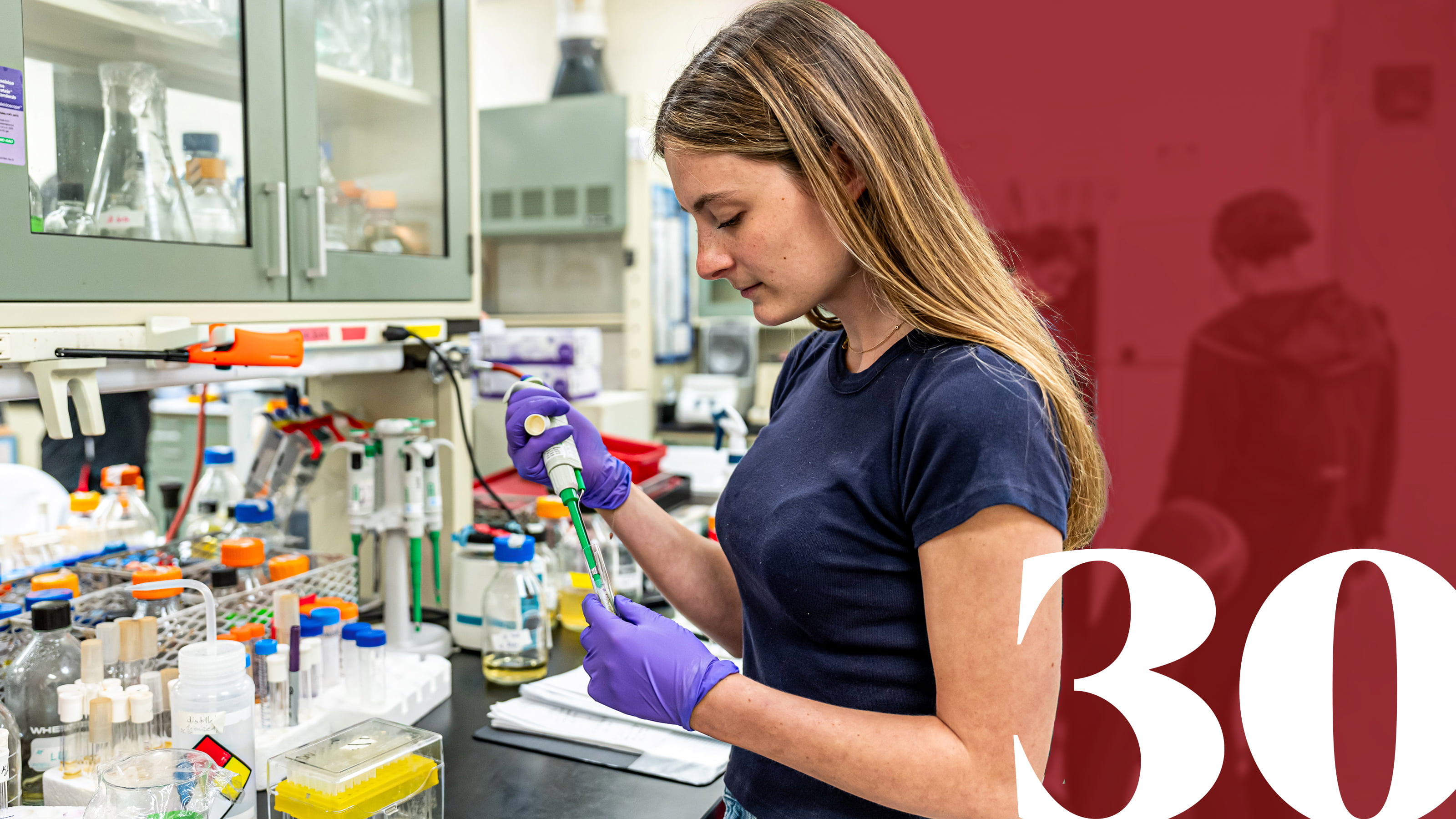 Health Sciences student in lab with red banner and 30 to the right