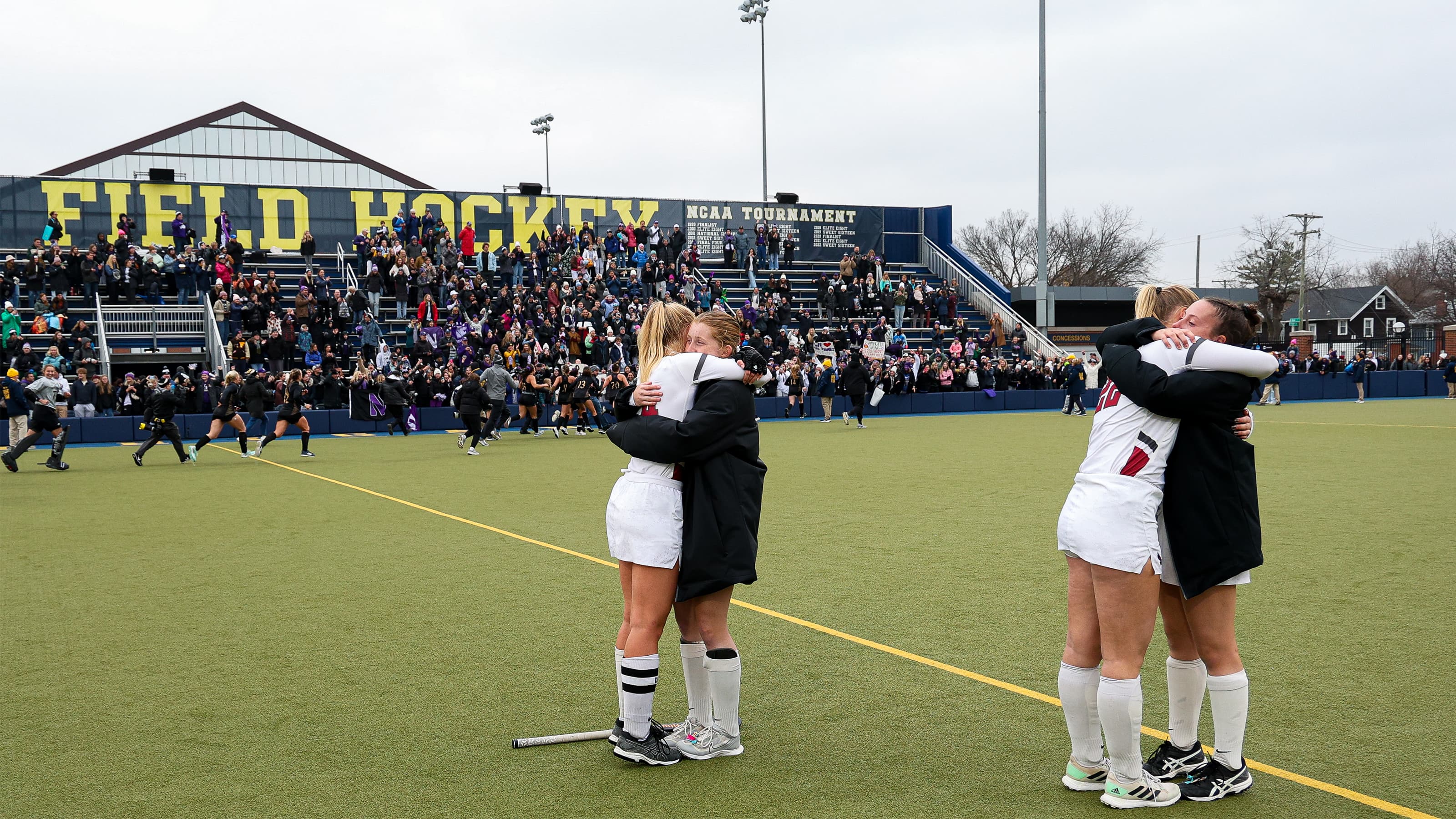 Field hockey opponents hug mid-field following the close of the game