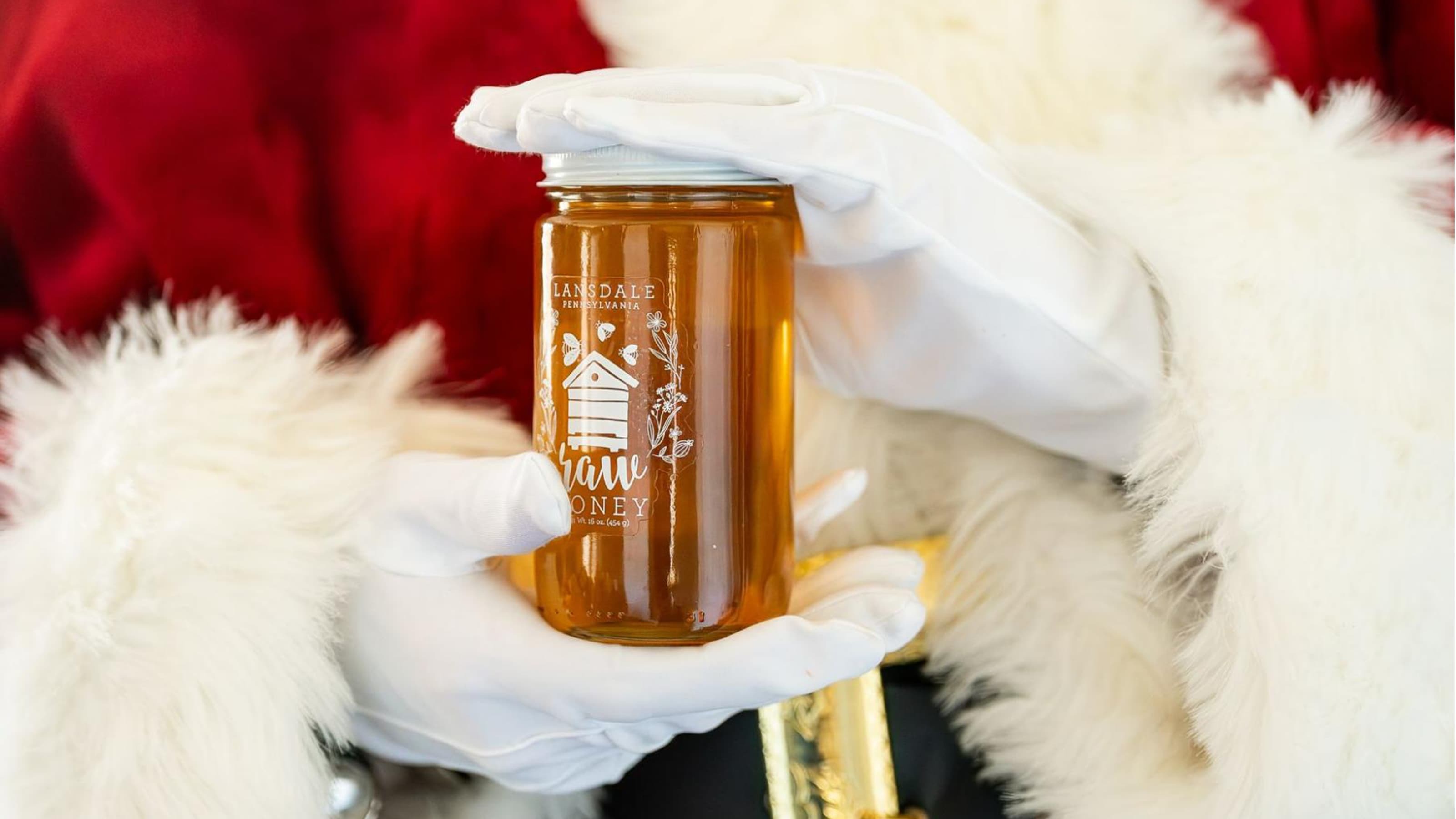 Santa's hands holding a bottle of honey.