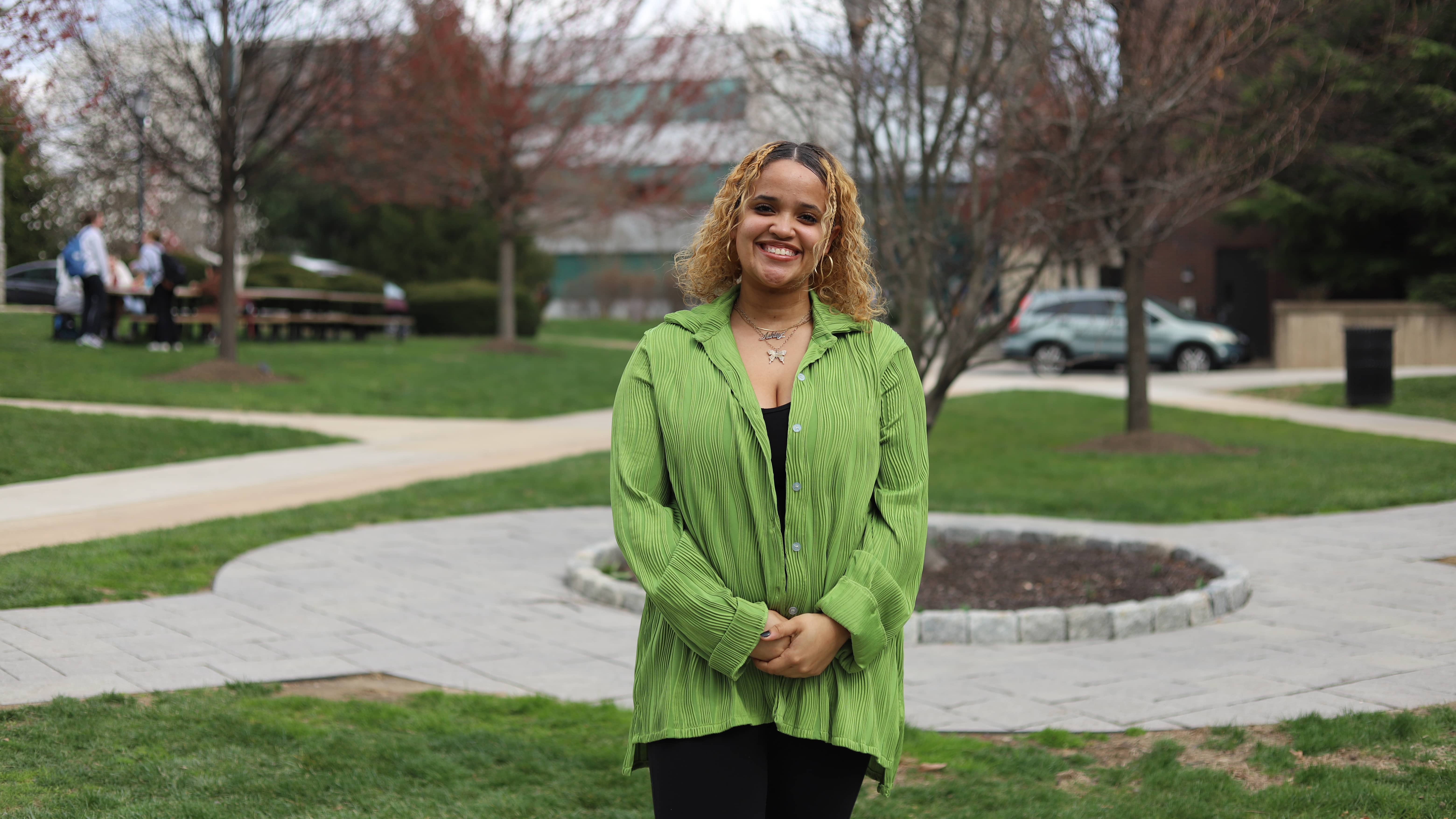 Ashley Morales wearing green shirt standing outside on Saint Joseph's campus