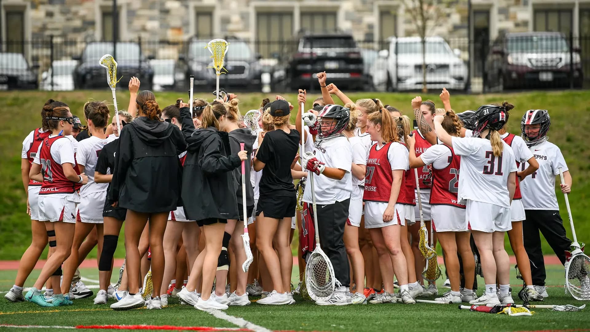 Saint Joseph's women's lacrosse team in field in team huddle