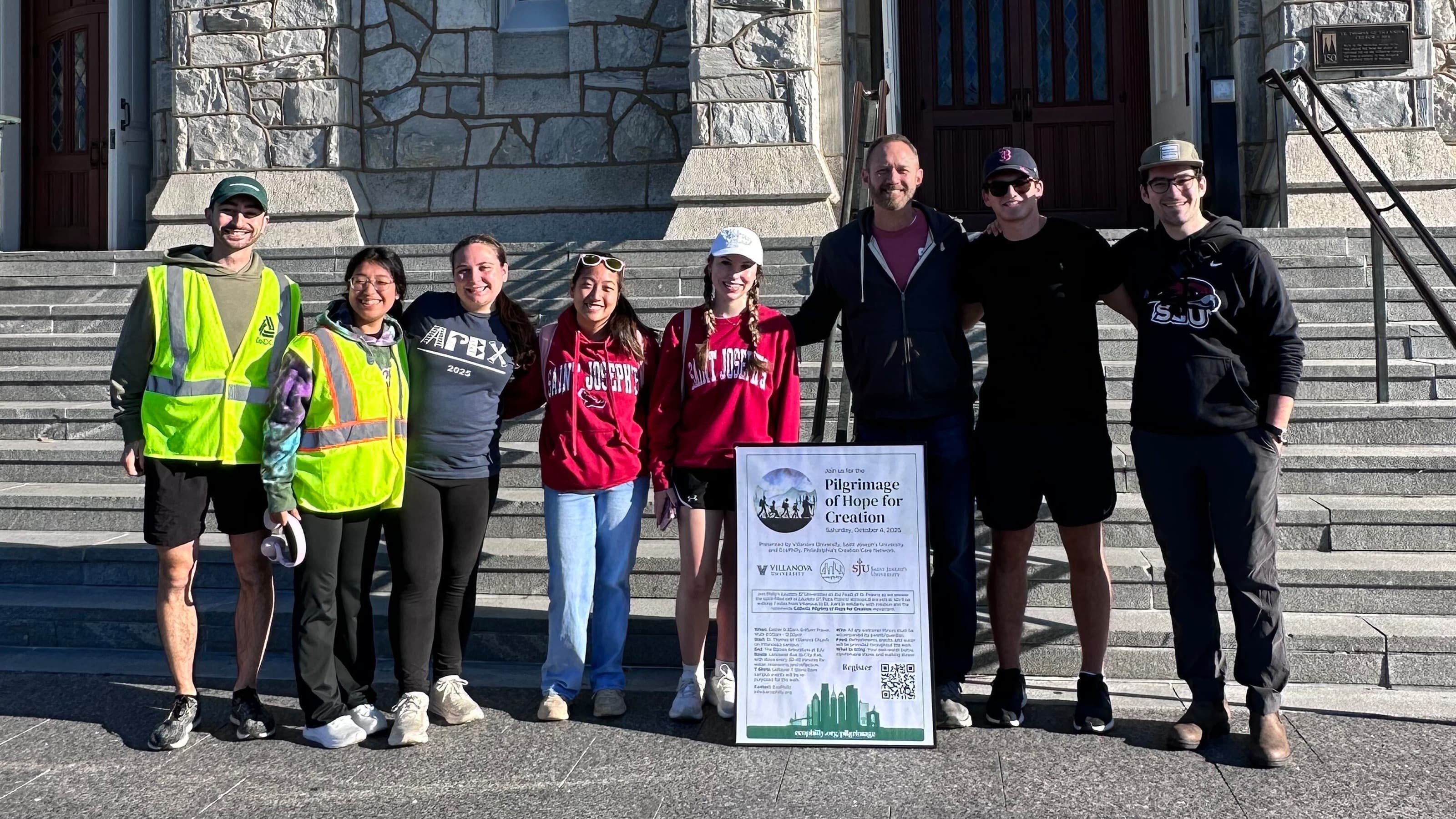 Students and staff smile at the camera at the base of the chapel steps.