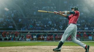 A professional male baseball player in mid swing with baseball bat outstretched having hit a baseball during a game