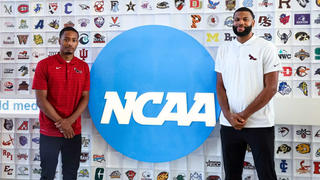 Saint Joseph's Xzayvier Brown and Phillip Lawrence-Ricks in front of blue NCAA sign and wall of basketball team logos