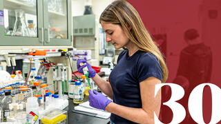 Health Sciences student in lab with red banner and 30 to the right