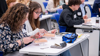 Two high school students practice suturing on a fake arm during their visit to Saint Joseph’s Lancaster location on Feb. 9.