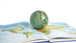 Open book with wide-image of a map with a globe on top of the pages.