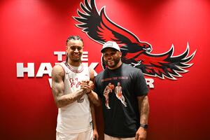 Erik Reynolds II, BS ’26, and Jameer Nelson posing in front of the Hawk logo.