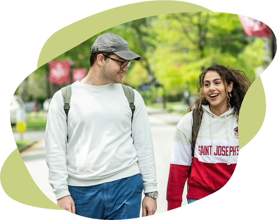 A male student and a female student walking on campus with a green background.