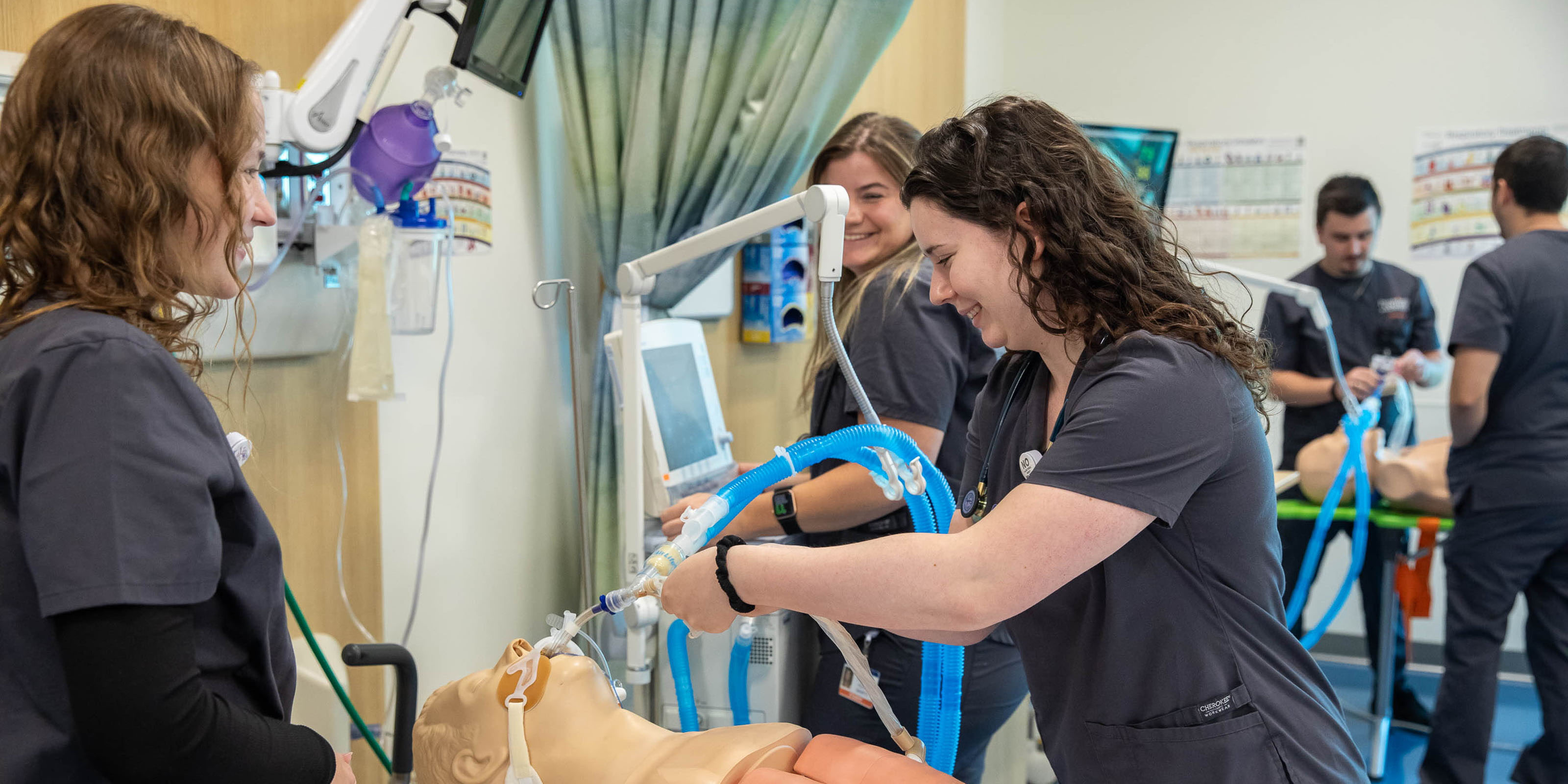 Three female Saint Joseph's nursing students in clinical classroom working on simulation patient