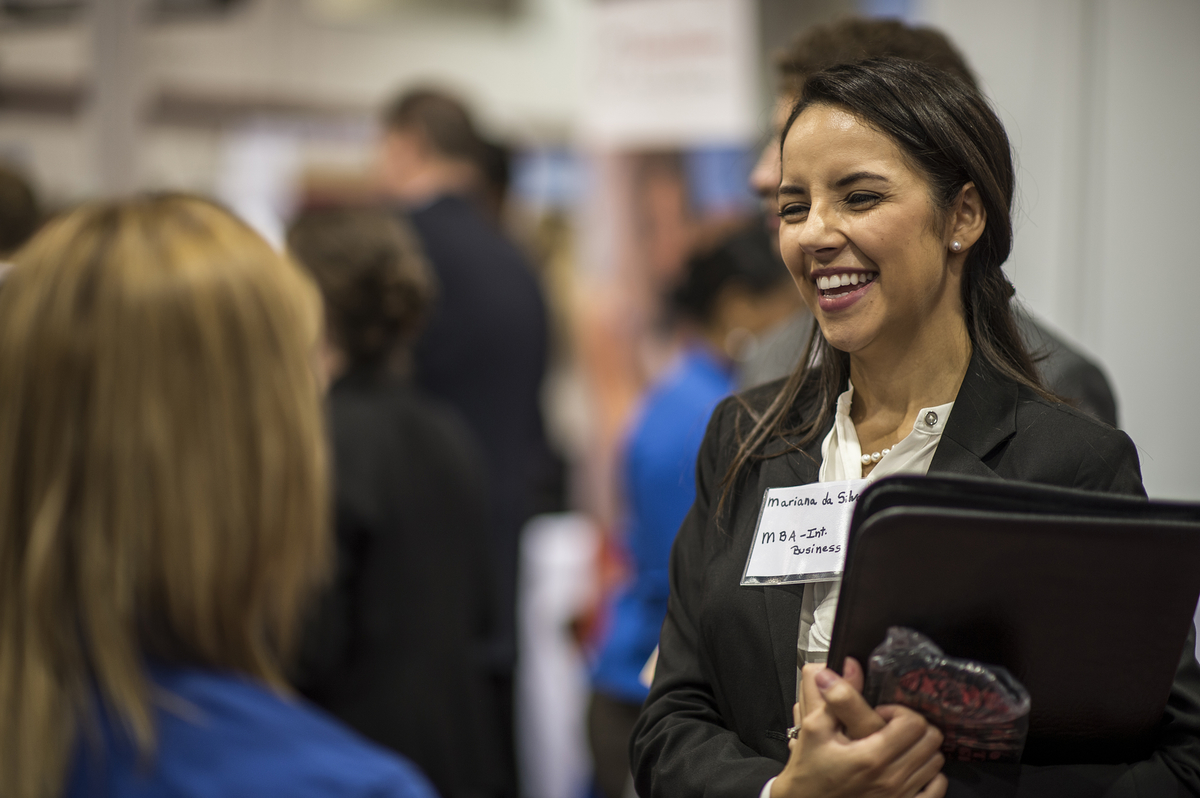 A young student smiles and chats with a potential employer at the Career Fair.