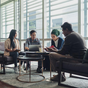 Photo of a group of individuals sitting around a table talking