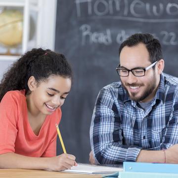 Male teacher helping middle school student in classroom