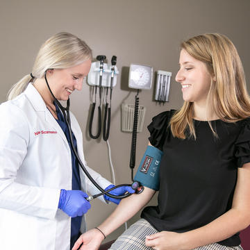 Saint Joseph's female Physician Assistant student checking female patients blood pressure