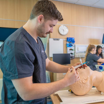 Male Saint Joseph's University nursing student practicing on simulation patient