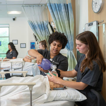 Two female Saint Joseph's University nursing student putting oxygen on a simulation patient