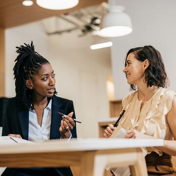 Two female business women having discussion at desk