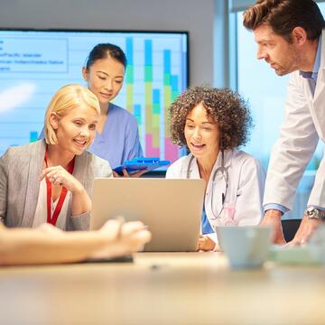 Pharmacy and business professionals in a meeting looking at computer