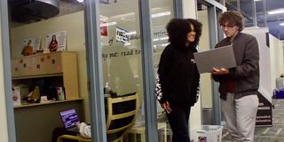 Two students conversing in front of Writing Center PLC location