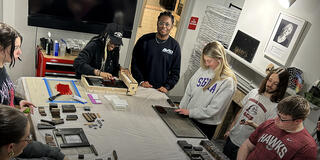 Graphic design students letterpress printing in classroom
