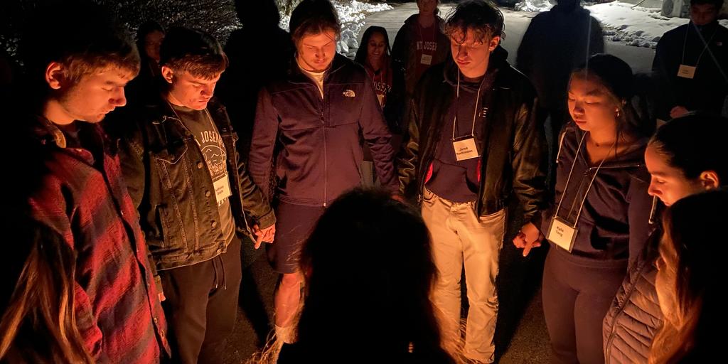 students holding hands around a glowing fire